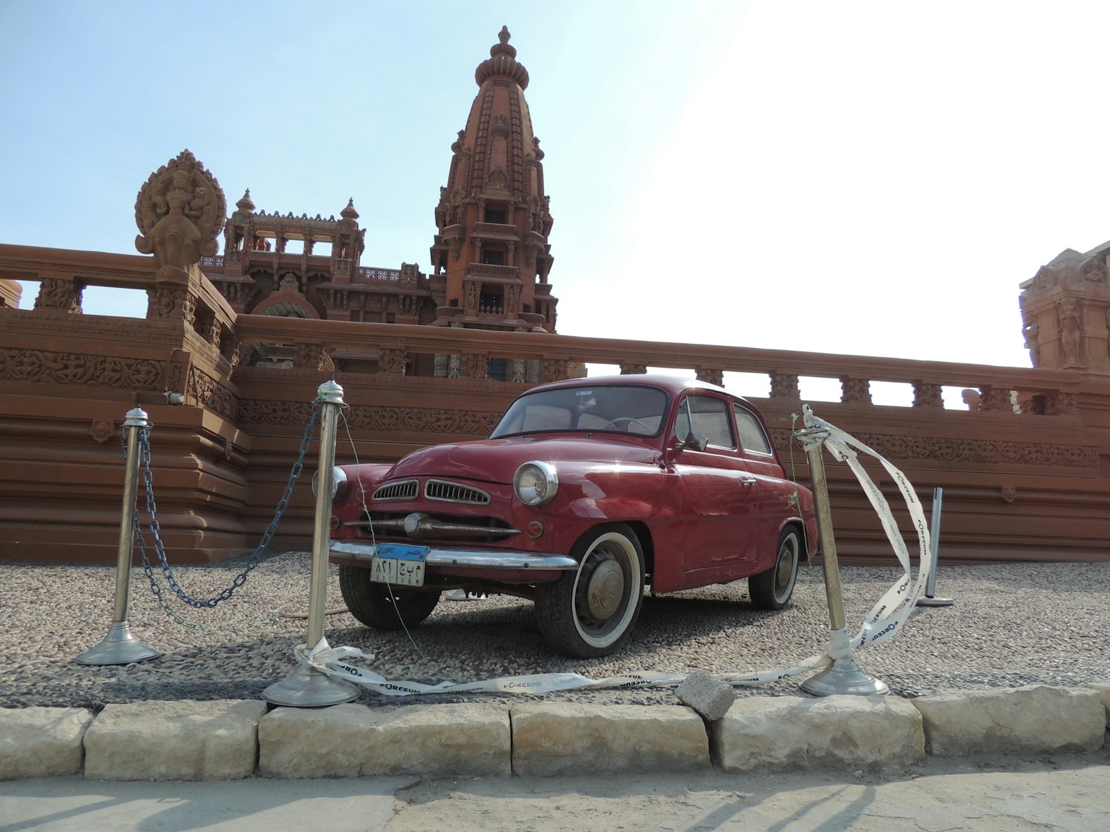 an old red car parked in front of a building